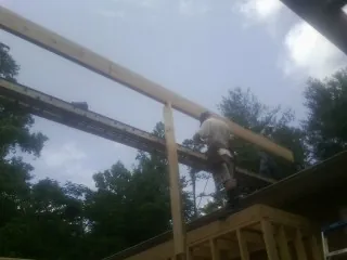 Carpenter setting a ridge beam over a new addition frame — Ice Dam Removal by Roofing Brothers in Andrews