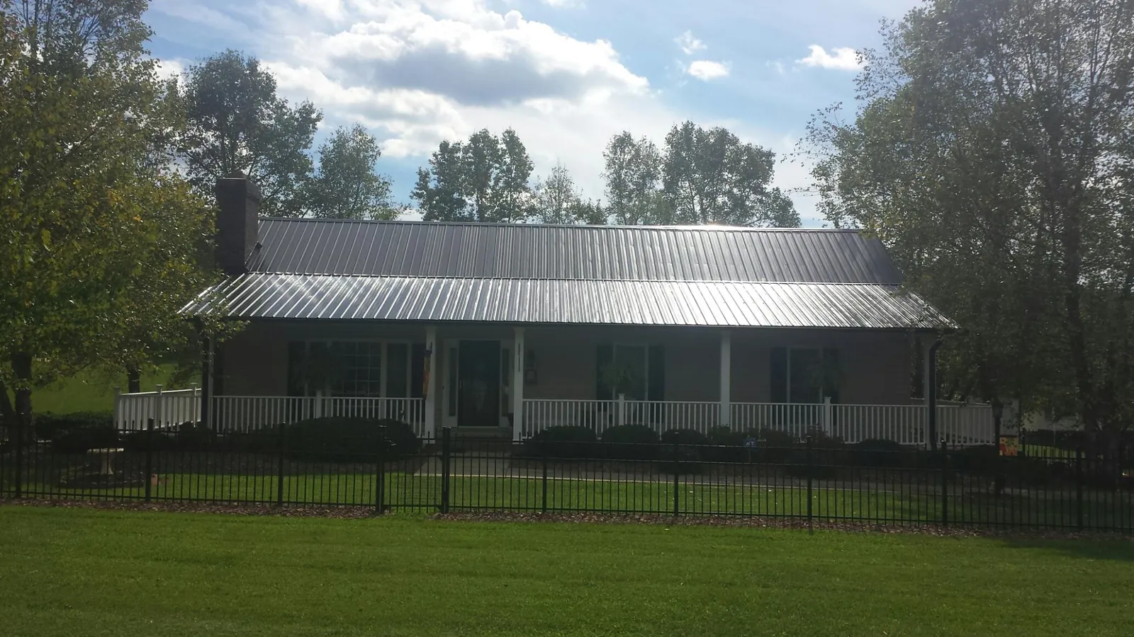 Gray metal roof on a brick ranch with a full width front porch — Gutter Guard Installation work by our crew in Andrews