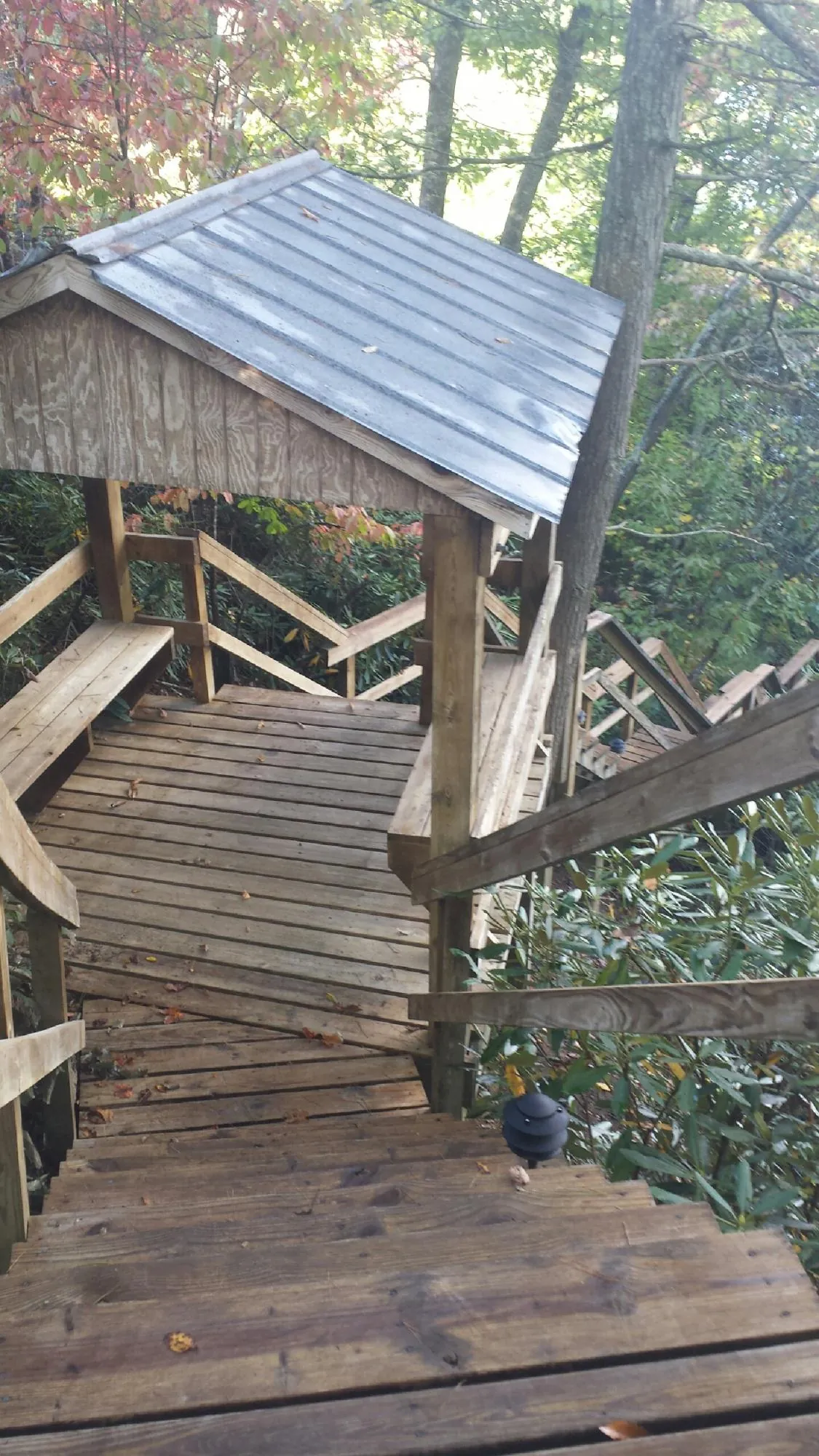 Metal roofed shelter over wooden steps on a wooded walkway — Skylight Repair & Installation work by our crew in Andrews